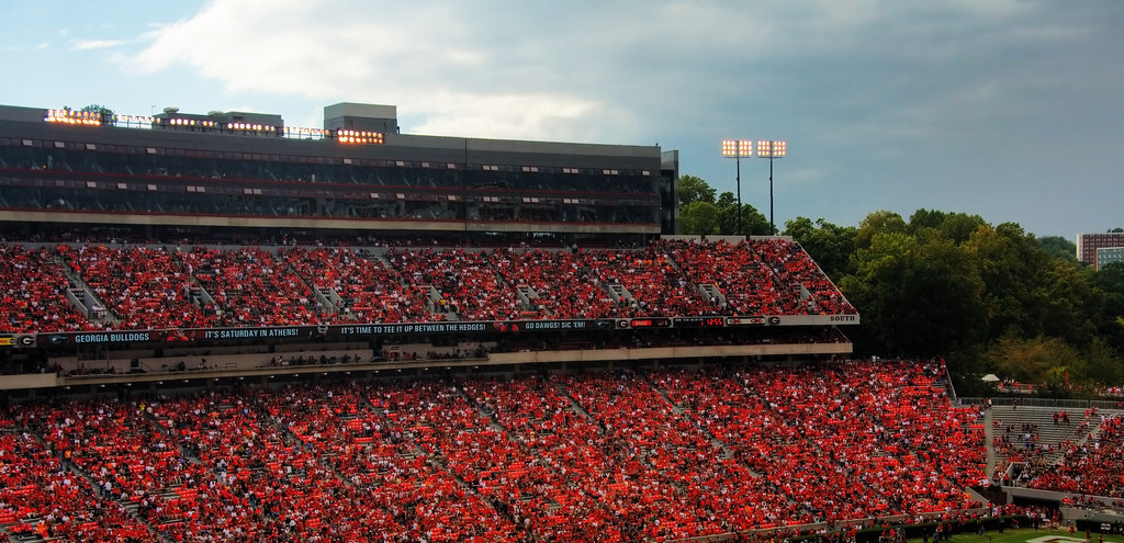 A view of Sanford Stadium during a home football game with the stands packed with fans all wearing red with the sky in the background.